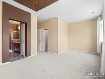 a view of an empty room with closet and a bathroom