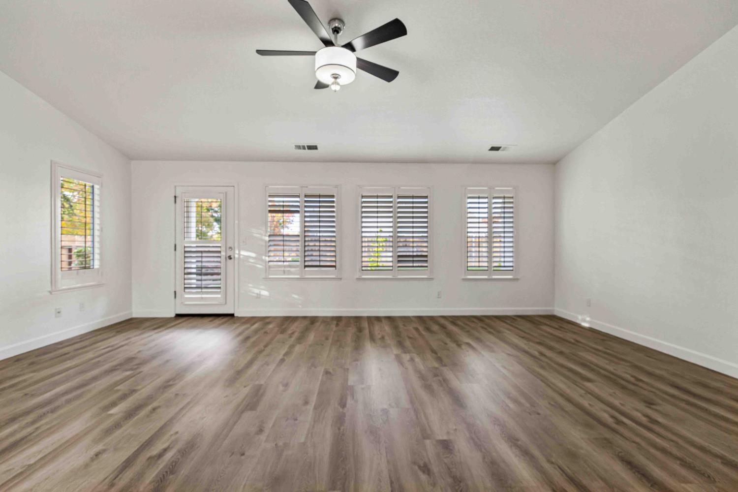995 West Springer Drive Turlock, CA 95382 - Photo 14 of 39 an empty room with wooden floor chandelier fan and windows