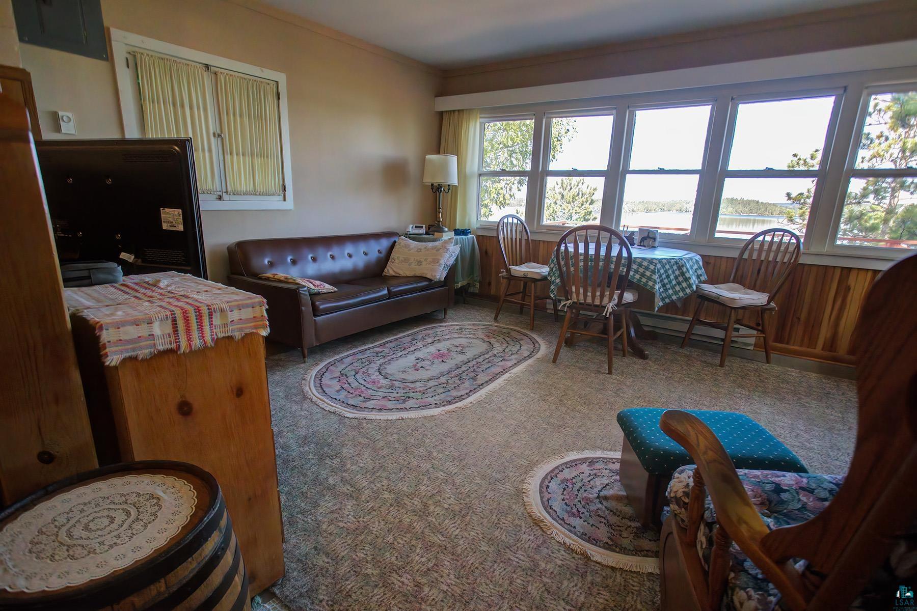2815 Schaeffer Road Ely, MN 55731 - Photo 29 of 37 Wall-to-wall carpeting with multiple area rugs, panel wood-finish wall accents, expansive window line, and ceiling-mounted light fixture