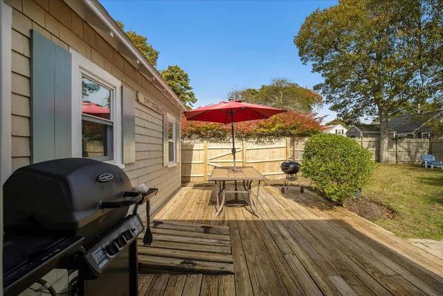 a view of a patio with table and chairs under an umbrella with wooden floor