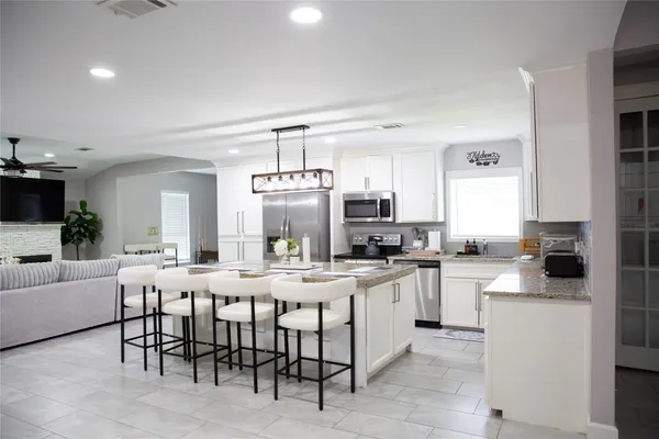 a kitchen with stainless steel appliances granite countertop a sink a stove a refrigerator cabinets and chairs
