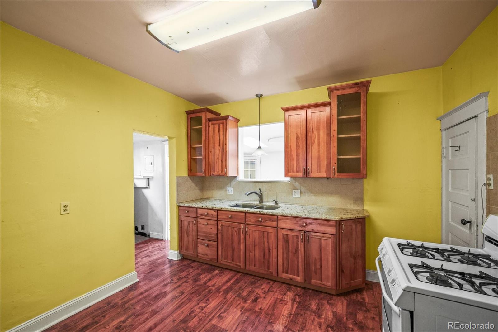 4551 Utica Street Denver, CO 80212 - Photo 11 of 32 a kitchen with stainless steel appliances granite countertop a sink cabinets and wooden floor