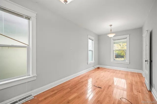 an empty room with wooden floor and windows