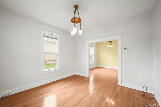 an empty room with wooden floor cabinet and windows
