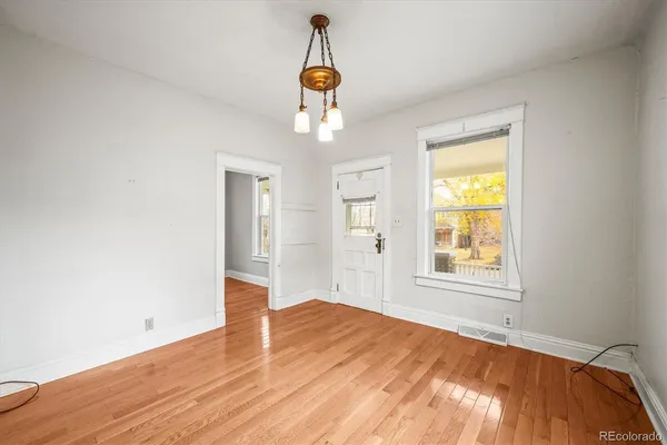 an empty room with wooden floor cabinet and windows