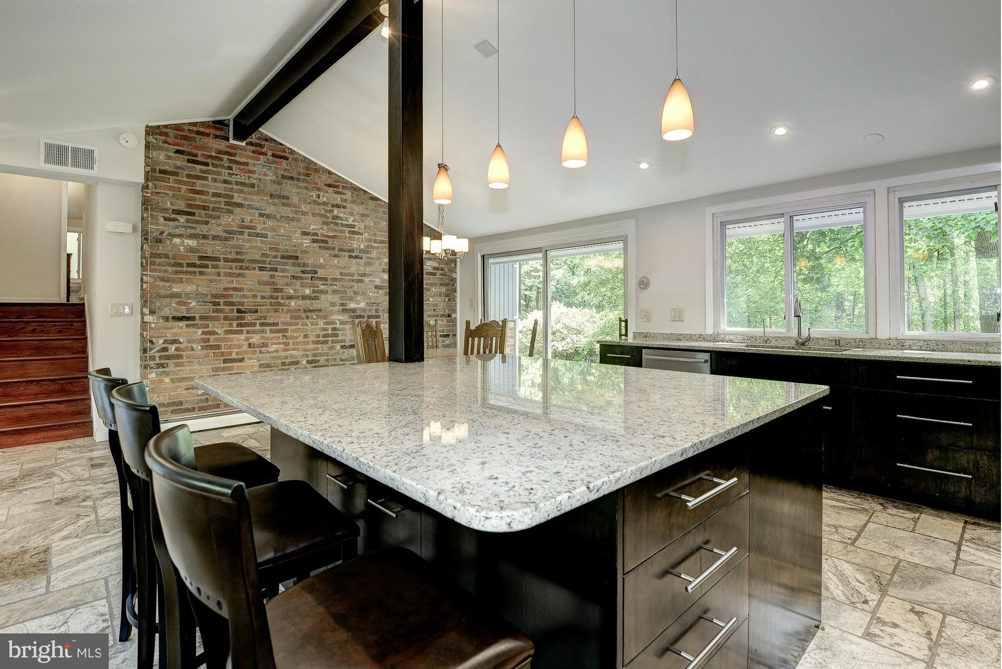 6718 Persimmon Tree Road Bethesda, MD 20817 - Photo 8 of 30 a kitchen with a kitchen island a stove a table and chairs in it