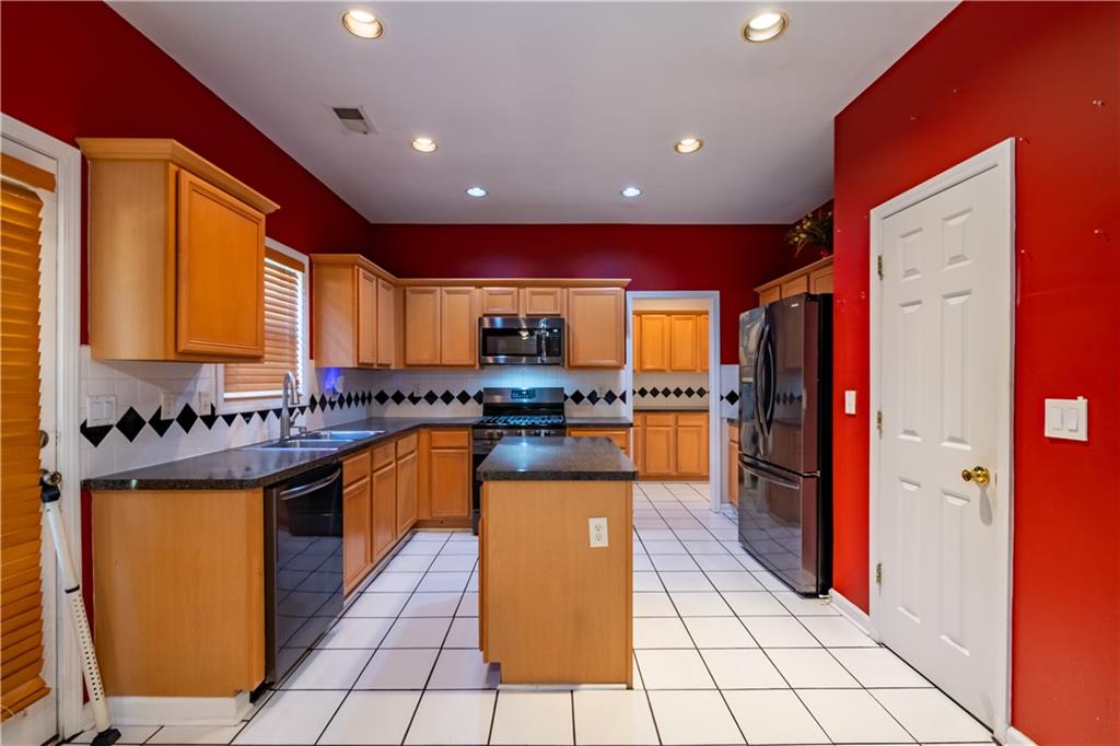 640 Fitzgerald Place Atlanta, GA 30349 - Photo 16 of 46 a kitchen with stainless steel appliances granite countertop a refrigerator a stove top oven and cabinets