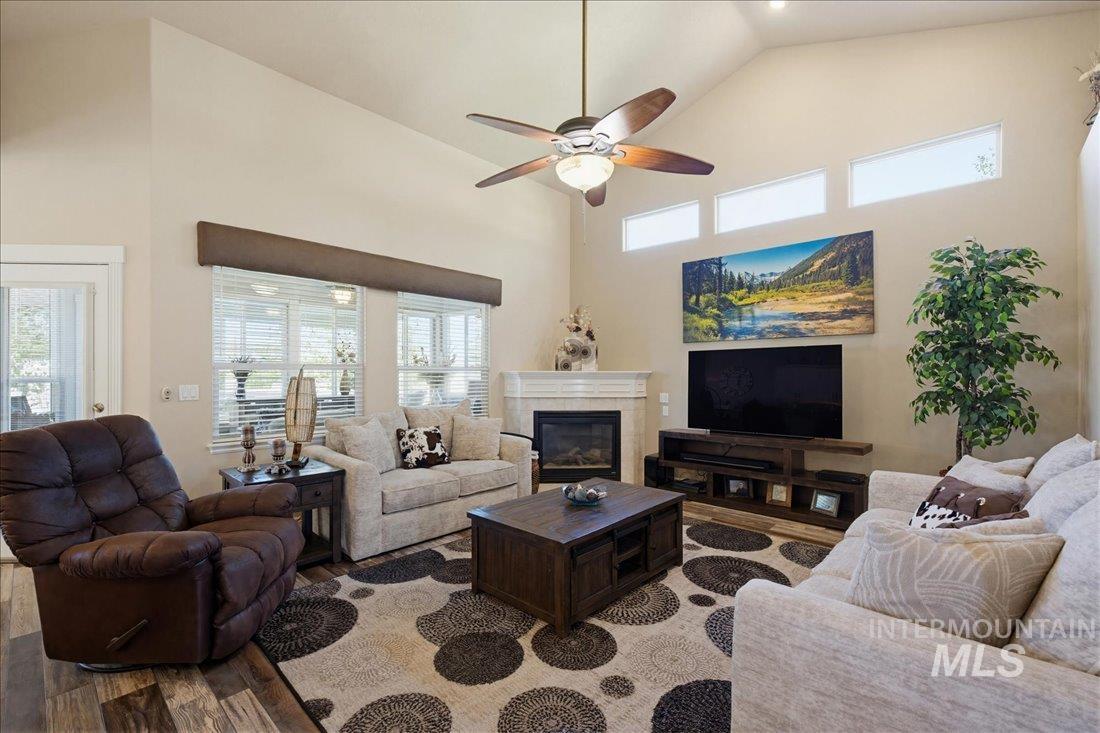24623 Falcon Lane Caldwell, ID 83607 - Photo 6 of 40 Spacious living area featuring a vaulted ceiling, wood-finish flooring, and a fireplace with a white mantel