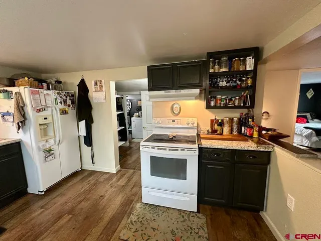 a kitchen with stainless steel appliances a stove top oven a refrigerator a sink and dishwasher with wooden floor