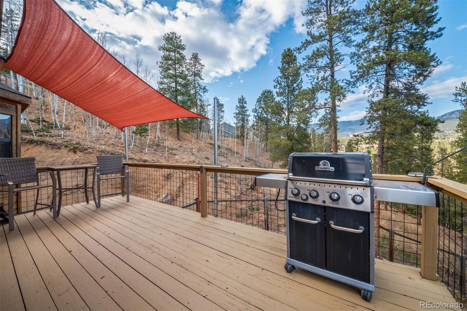 609 Gold Flake Terrace Bailey, CO 80421 - Photo 37 of 47 a balcony with a table and chairs under an umbrella