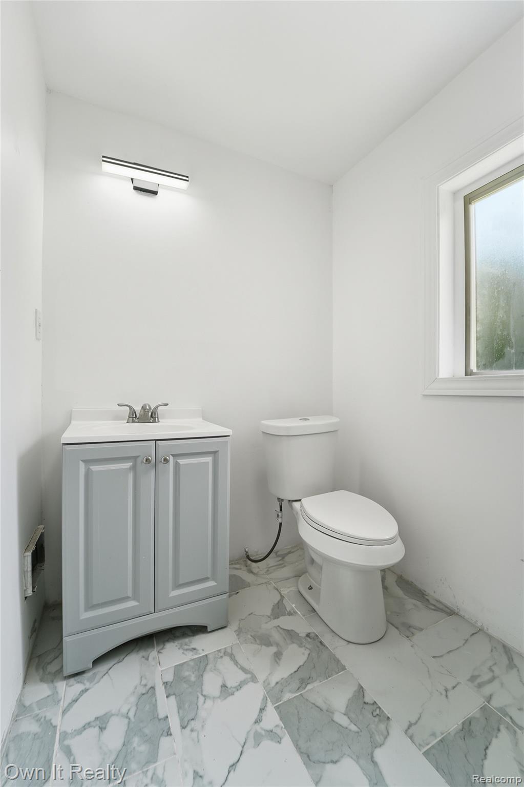 17351 Appoline Street Detroit, MI 48235 - Photo 14 of 34 Bathroom featuring a light gray vanity with a single sink, white countertop, white toilet, and patterned floor tiling