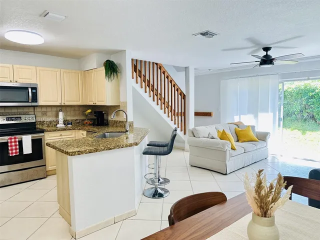 a living room with stainless steel appliances furniture a rug and a view of kitchen