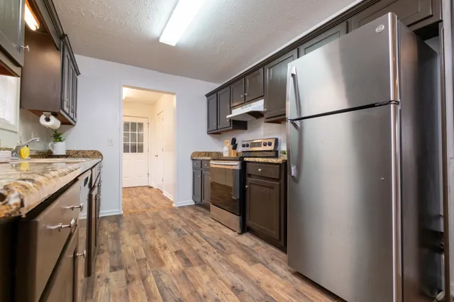 a kitchen with stainless steel appliances granite countertop a refrigerator a stove a sink and a microwave