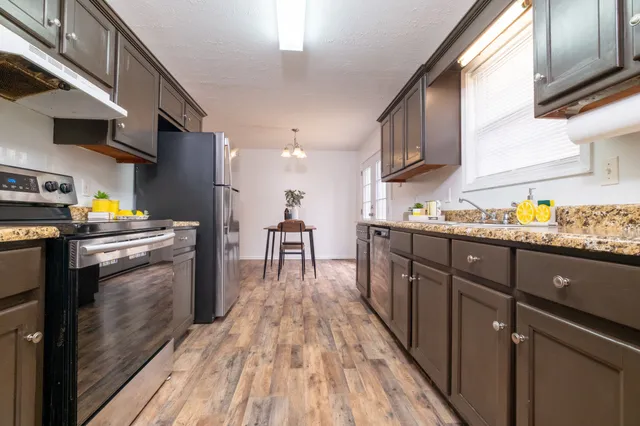 a kitchen with stainless steel appliances granite countertop a refrigerator a stove and a wooden floors