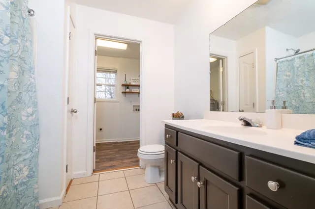 a bathroom with a granite countertop sink a toilet a mirror and shower