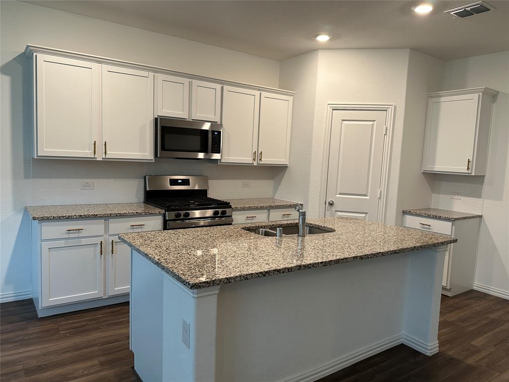 768 Hawthorn Street Princeton, TX 75407 - Photo 5 of 23 a kitchen with granite countertop a sink a stove a microwave and cabinets