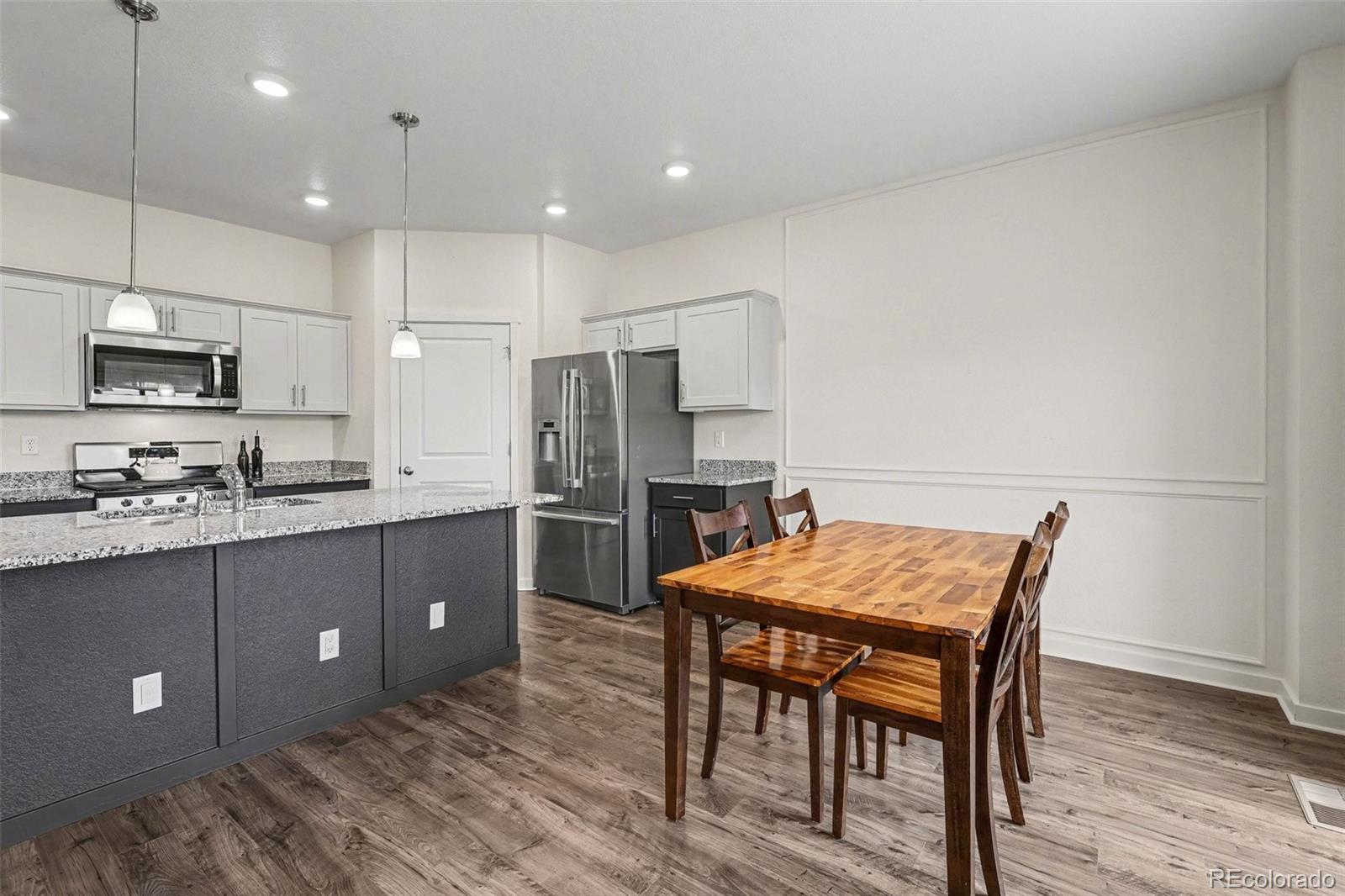 2226 Monte Vista Court Fort Lupton, CO 80621 - Photo 8 of 25 a kitchen with stainless steel appliances a refrigerator a stove a sink a dining table and chairs