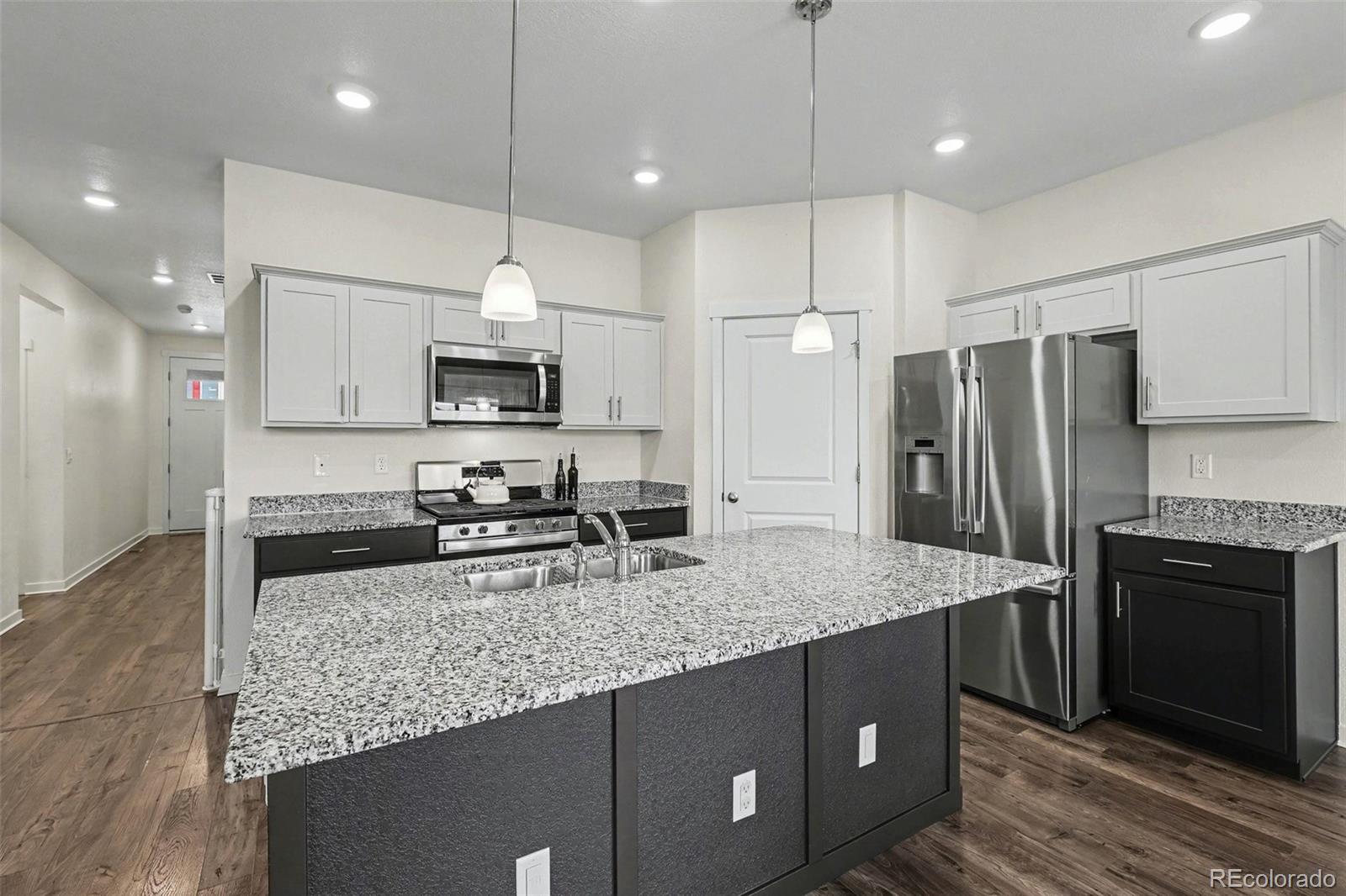2226 Monte Vista Court Fort Lupton, CO 80621 - Photo 10 of 25 a kitchen with stainless steel appliances granite countertop a sink refrigerator and microwave