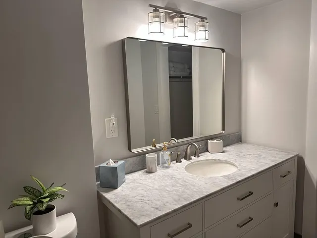 a bathroom with a granite countertop sink toilet and a mirror