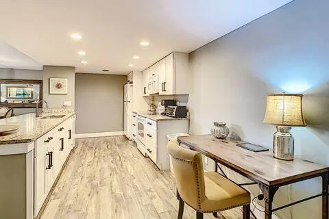 a kitchen with stainless steel appliances kitchen island granite countertop a sink cabinets and wooden floor