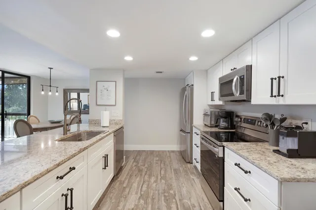 a kitchen with granite countertop kitchen island stainless steel appliances a sink a stove a counter space and cabinets