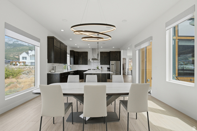 1445 Jacob Road Sandy, UT 84092 - Photo 13 of 52 Open-concept dining area with wood-finish flooring, a modern chandelier, and large windows