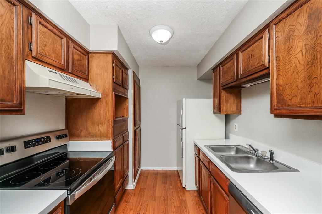 9696 Walnut Street, Unit 1216 Dallas, TX 75243 - Photo 12 of 19 Galley kitchen featuring wood-finish cabinetry, white countertops, and wood-finish flooring