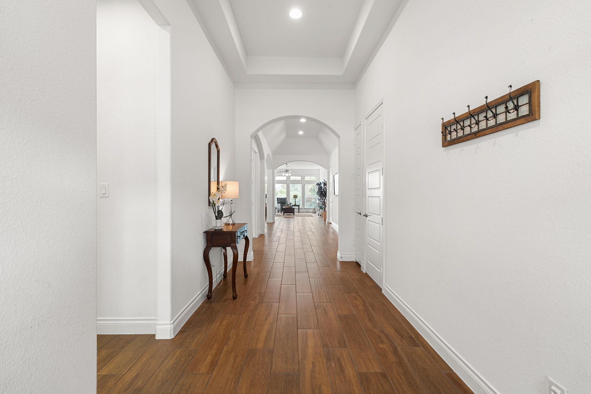 1908 Woolsey Way Leander, TX 78641 - Photo 9 of 36 Oversized hallway with warm wood tones guides the eye through arched doorways to sunlit living spaces.