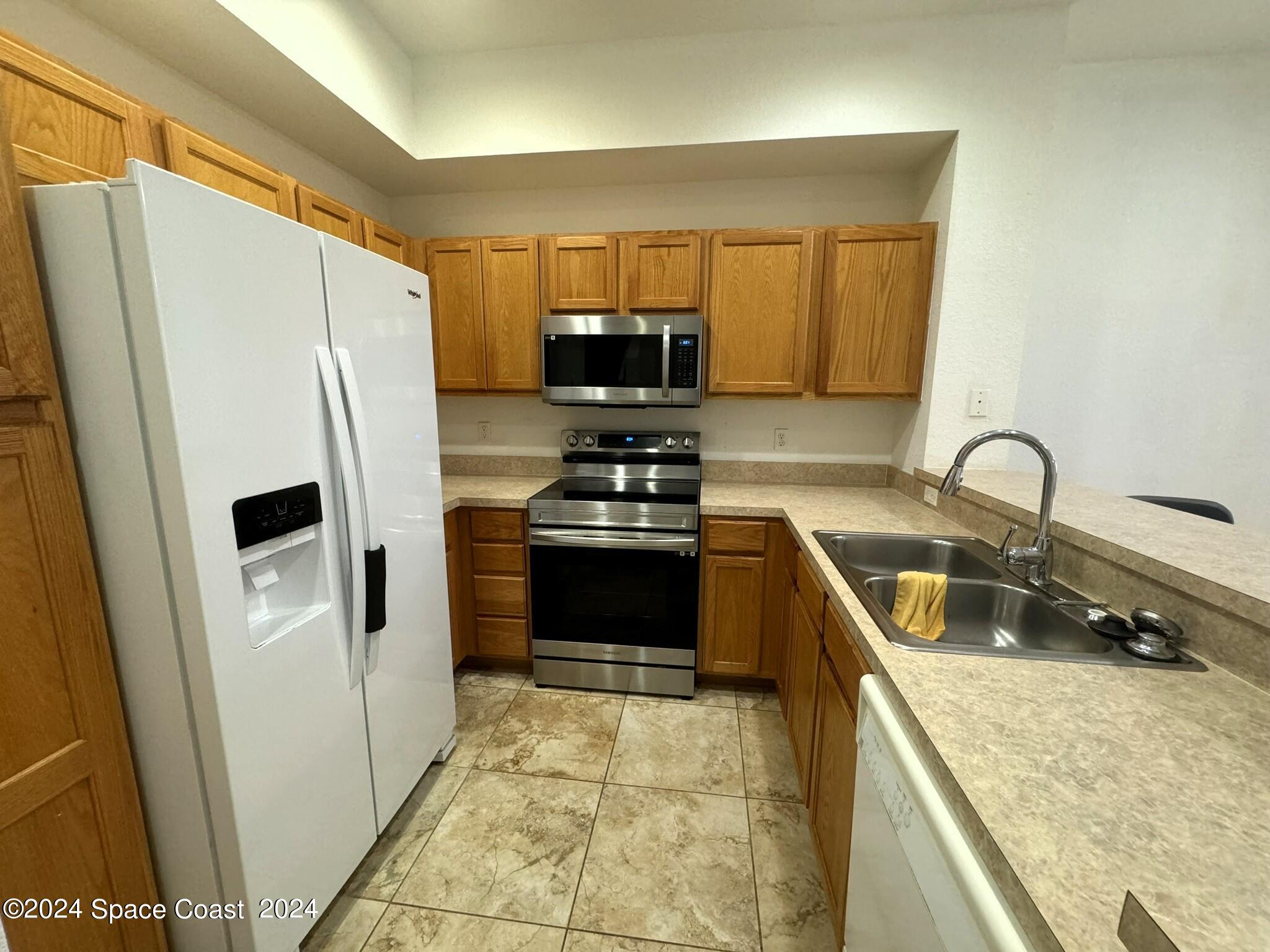3975 Almeida Court, Unit 105 Melbourne, FL 32901 - Photo 3 of 18 a kitchen with a refrigerator a stove and a sink