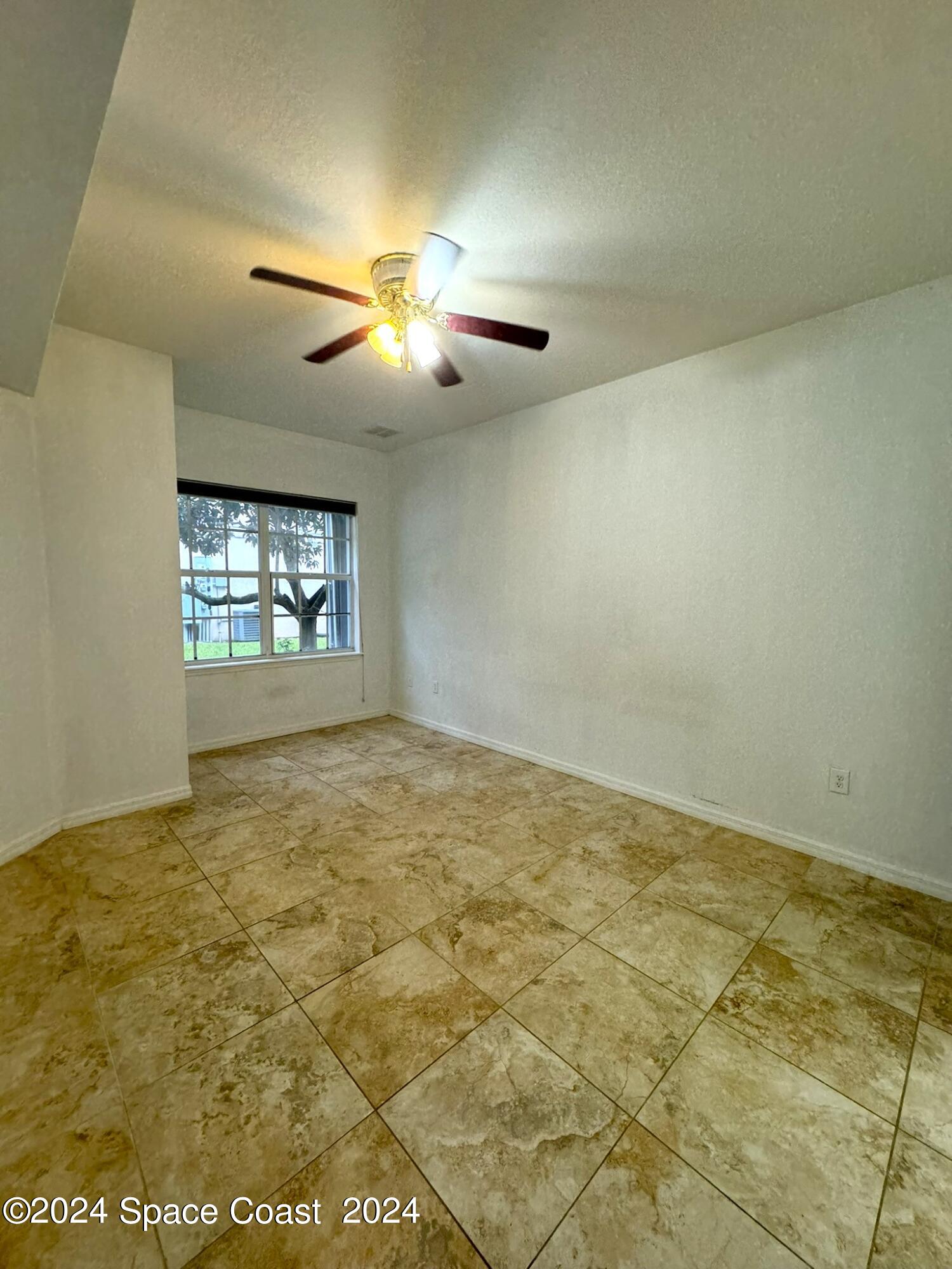 3975 Almeida Court, Unit 105 Melbourne, FL 32901 - Photo 4 of 18 an empty room with windows and ceiling fan view