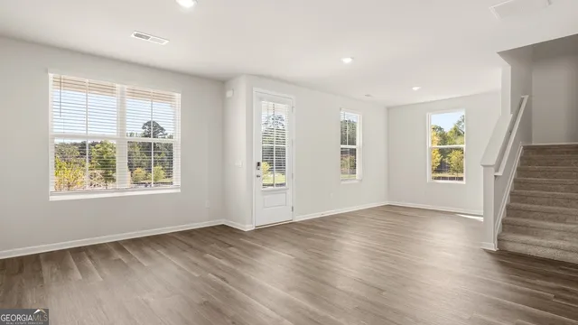 a view of an empty room with wooden floor and a window