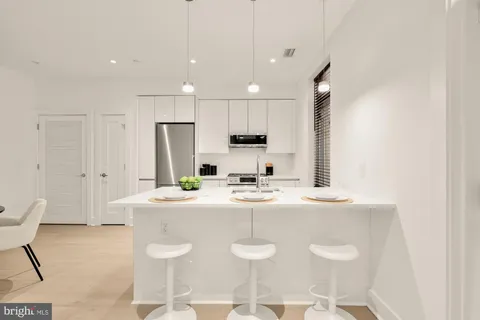 a kitchen with kitchen island a white counter top space a sink appliances and cabinets