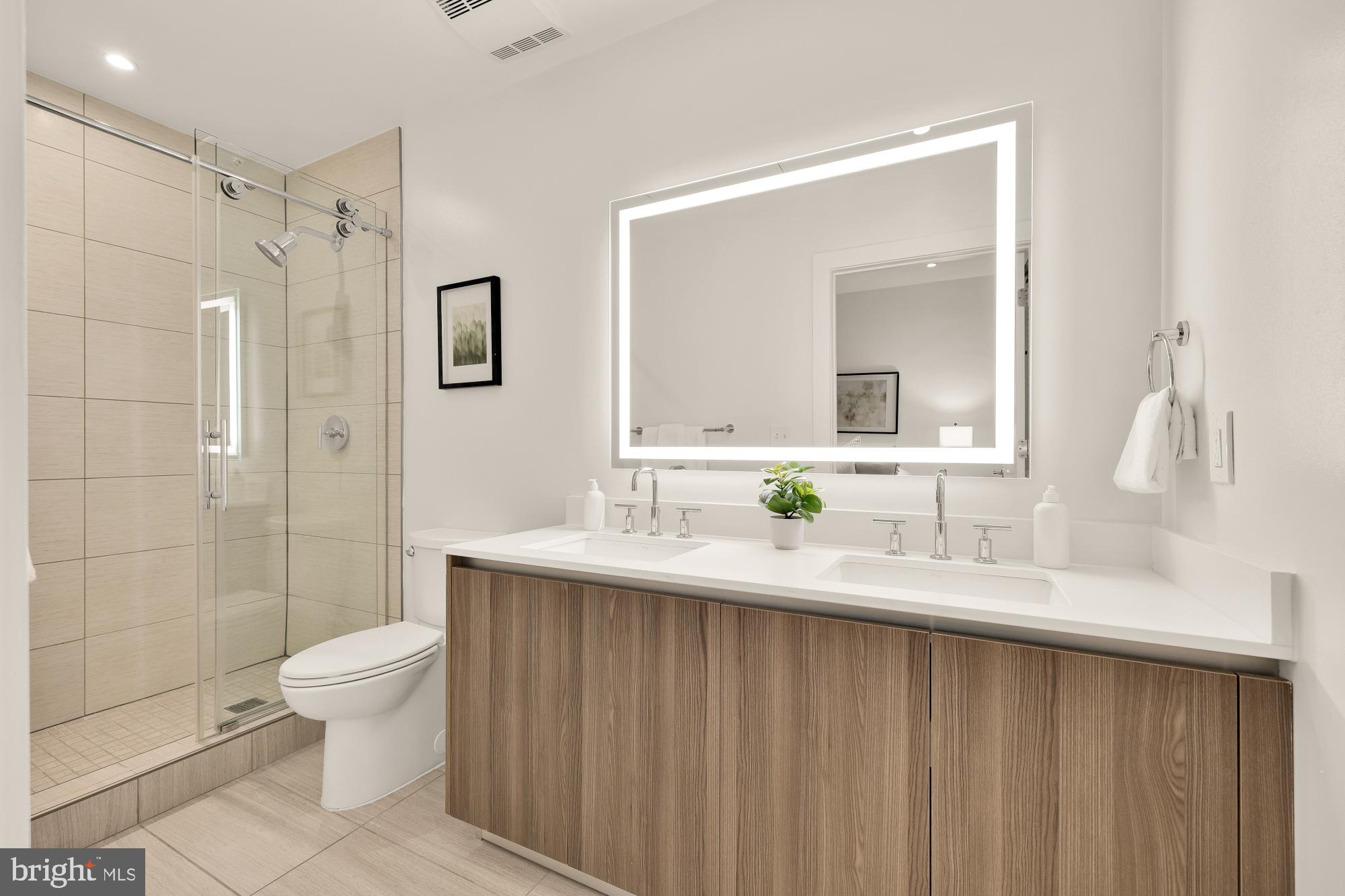 1745 N Street Northwest, Unit 104 Washington, DC 20036 - Photo 21 of 28 a bathroom with a double vanity sink toilet mirror and shower