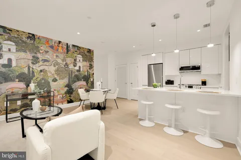 a living room with couches and kitchen view with wooden floor