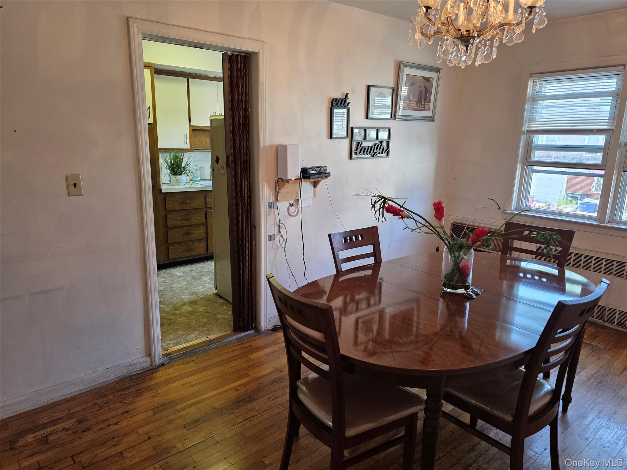 150-29 77th Road Queens, NY 11367 - Photo 4 of 8 Dining area featuring wood-type flooring, a chandelier, and radiator heating unit