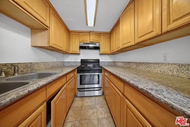 a kitchen with granite countertop wooden cabinets and a stove top oven