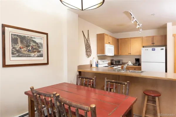 a kitchen with stainless steel appliances granite countertop a dining table chairs and a refrigerator
