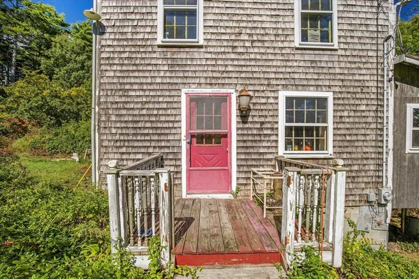 a view of a wooden house with a yard and wooden fence
