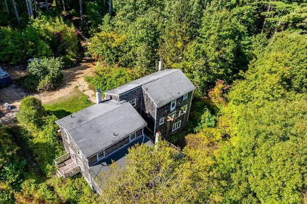 an aerial view of a house with swimming pool and large trees