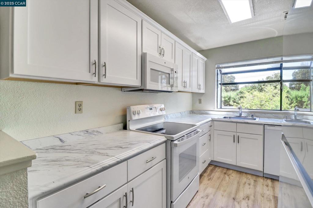1300 Walden Road Walnut Creek, CA 94597 - Photo 9 of 52 a kitchen with granite countertop white cabinets and white appliances
