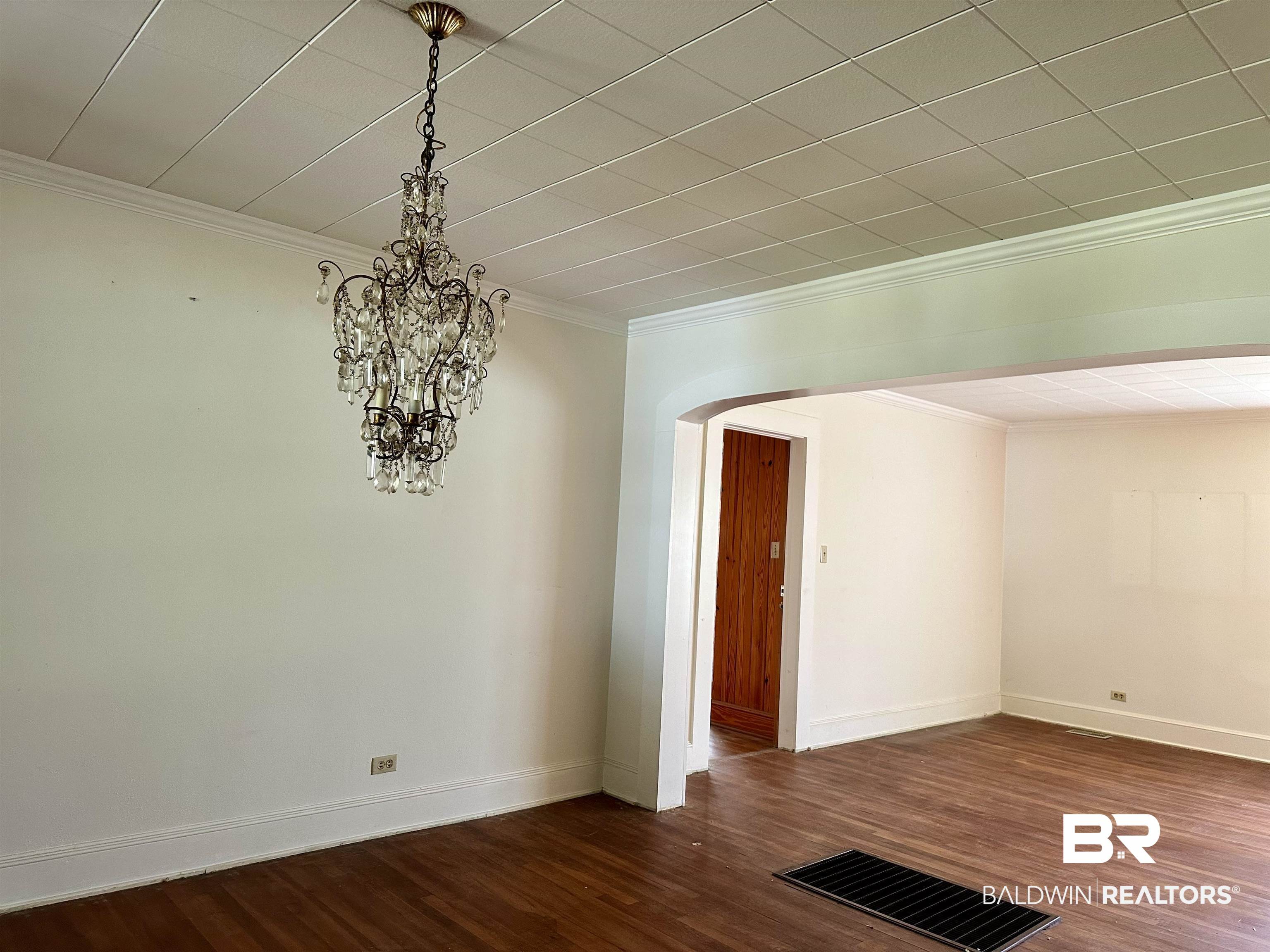 3556 Damascus Road Brewton, AL 36426 - Photo 5 of 17 Unfurnished room with visible vents, dark wood finished floors, ornamental molding, an inviting chandelier, and arched walkways