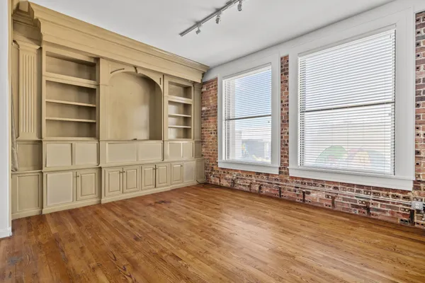 a view of an empty room with a window and wooden floor