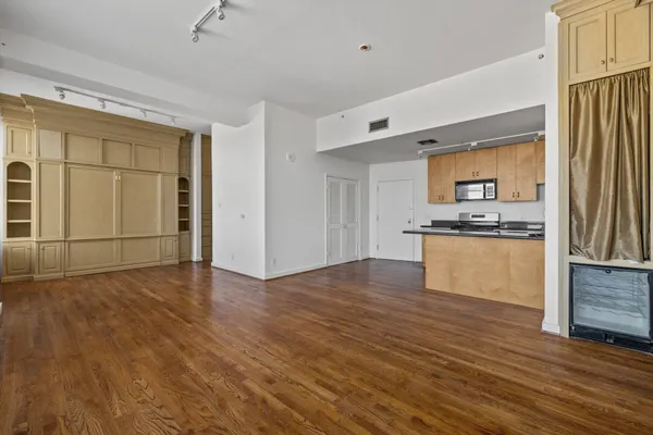 a view of kitchen with stainless steel appliances wooden floor and cabinets