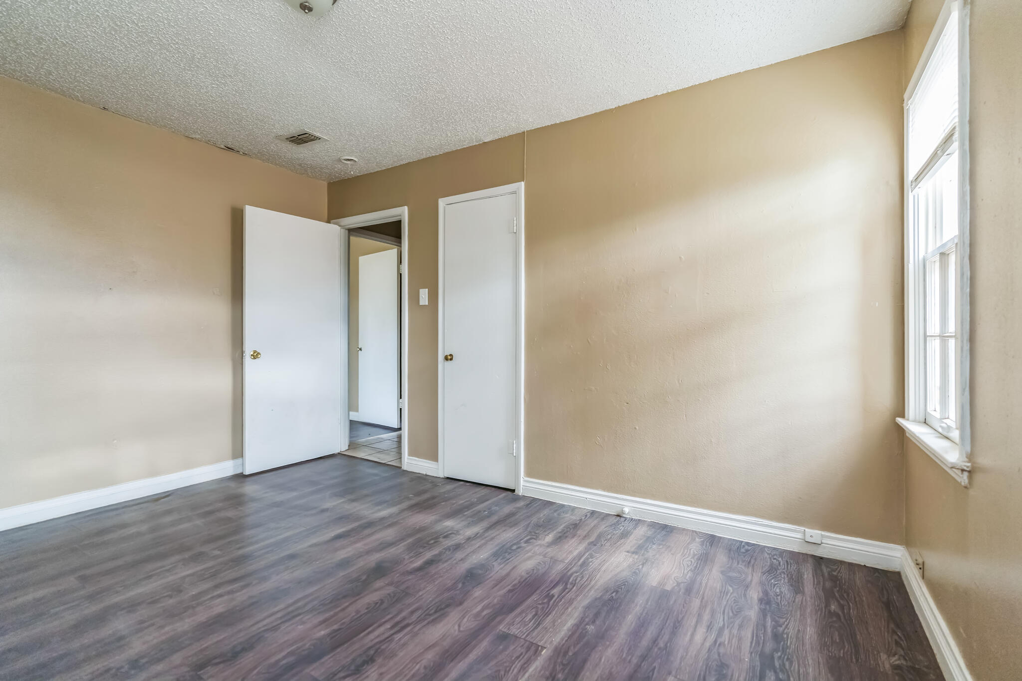 1510 33rd Street Lubbock, TX 79411 - Photo 12 of 33 a view of an empty room with wooden floor and a window