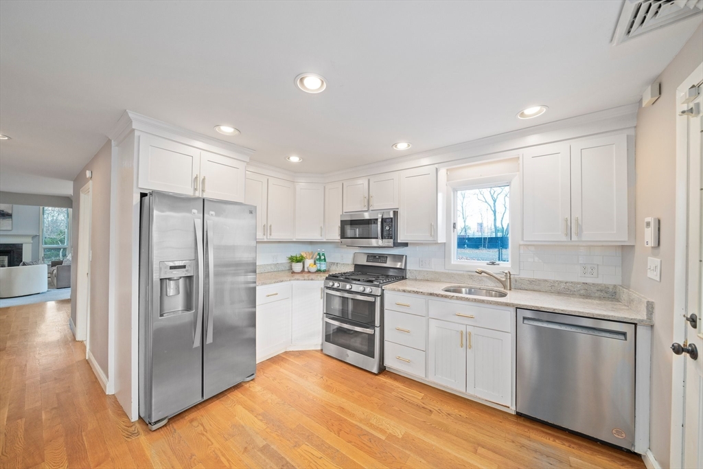 91 Prospect Street Canton, MA 02021 - Photo 15 of 41 a kitchen with stainless steel appliances granite countertop a refrigerator a sink dishwasher a stove with white cabinets and wooden floor