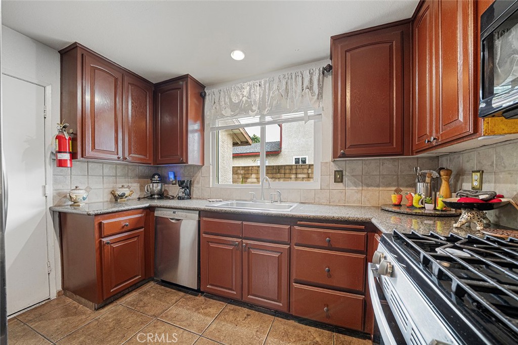 15465 Raymond Avenue Fontana, CA 92336 - Photo 2 of 27 a kitchen with a sink stove top oven and cabinets