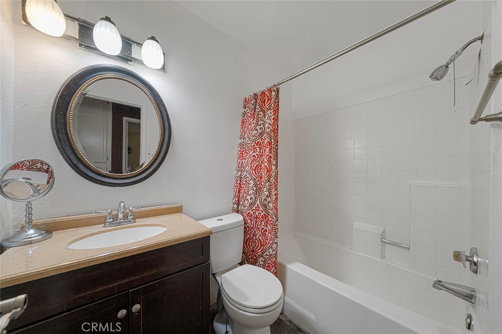 15465 Raymond Avenue Fontana, CA 92336 - Photo 6 of 27 a bathroom with a granite countertop toilet a sink and a mirror
