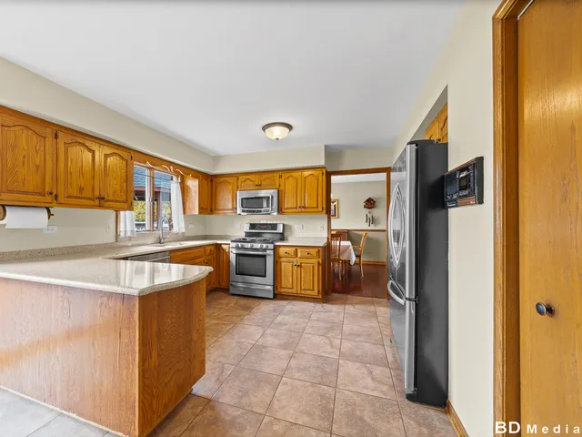 a large kitchen with stainless steel appliances granite countertop a large counter top a stove and a refrigerator