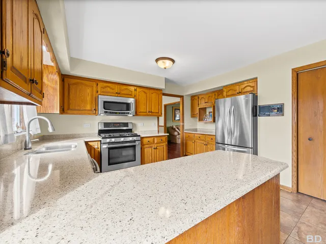 a kitchen with stainless steel appliances granite countertop a sink a stove top oven a refrigerator with grey cabinets and wooden floor