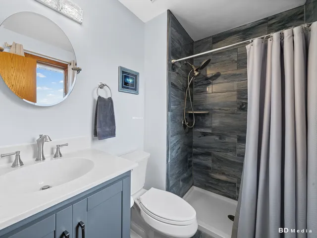 a bathroom with a sink a mirror a toilet and shower